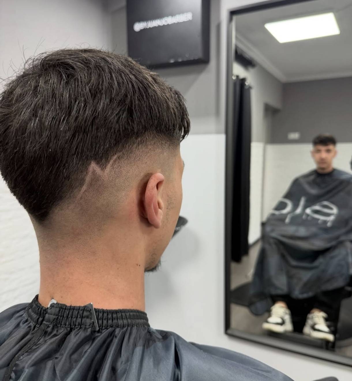 Corte de pelo moderno para hombre con degradado fade y diseño de líneas hecho en la barbería by Juanjo Barber en Ayamonte.